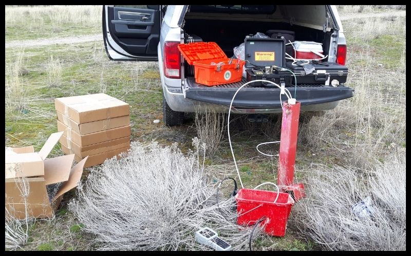 Back of a truck parked on the ground with a variety of testing supplies set up