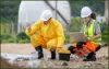 Two scientists in protective gear taking samples